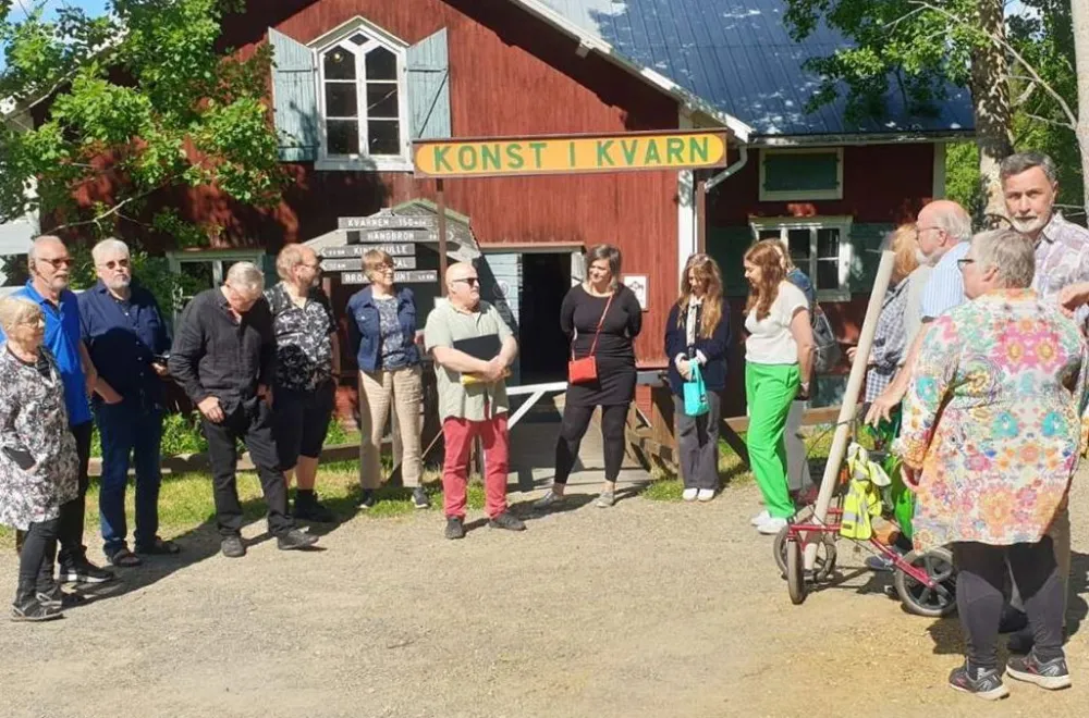 Åke Bäckström personer utanför en röd kvarnbyggnad med skylten konst i kvarn