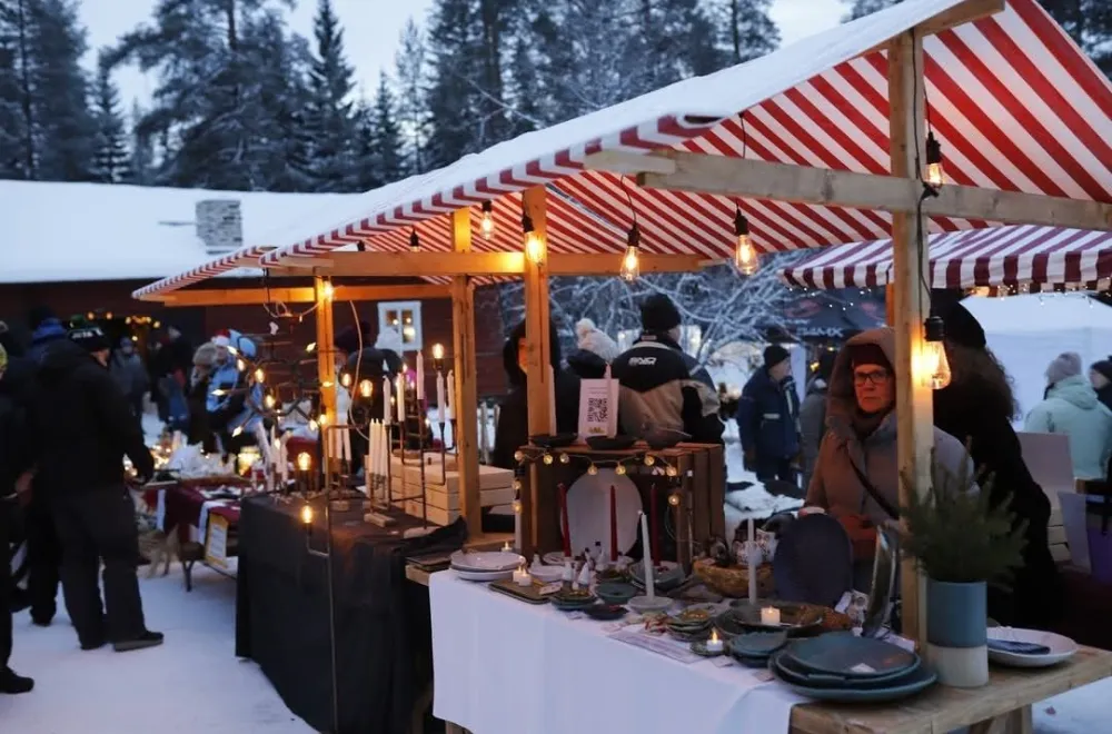 Outdoor Christmas market in the snow with red-and-white striped stalls.