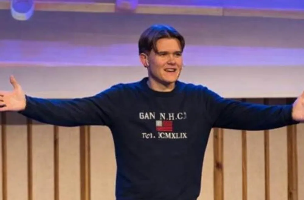 En ung kille som föreläser och sträcker ut sina armar mot publiken