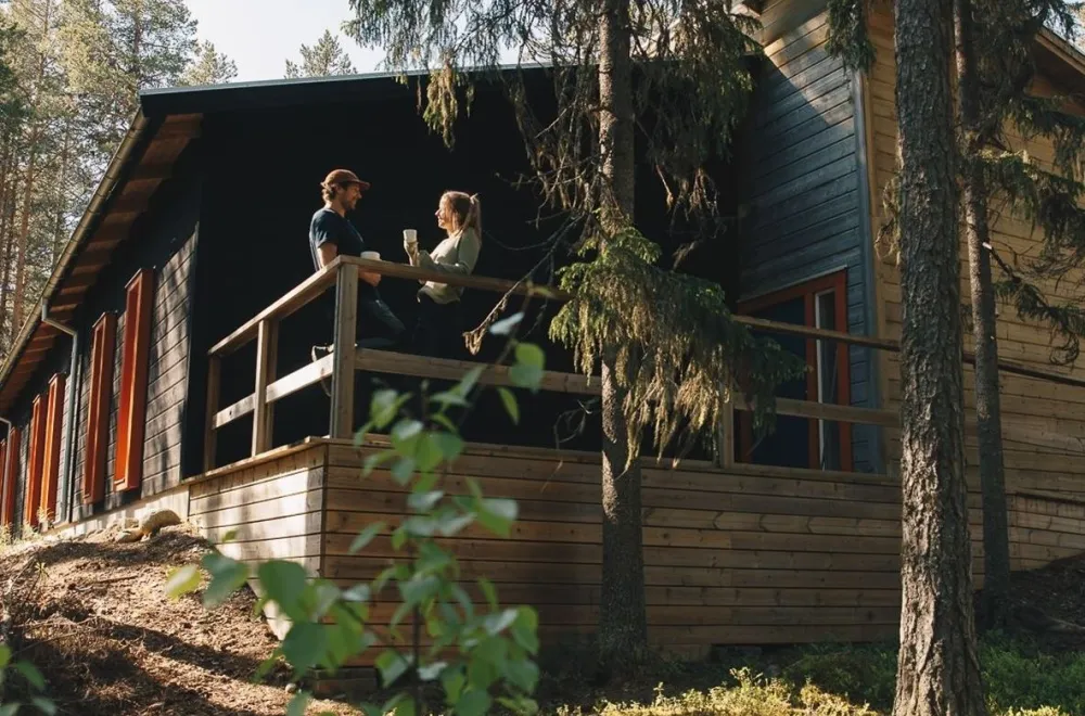 träbyggnad med röda fönsterfoder i en skog sommartid