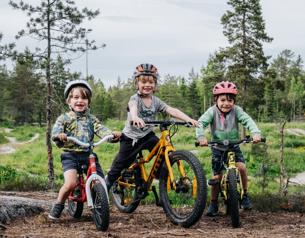 Tre barn på cykel i terräng