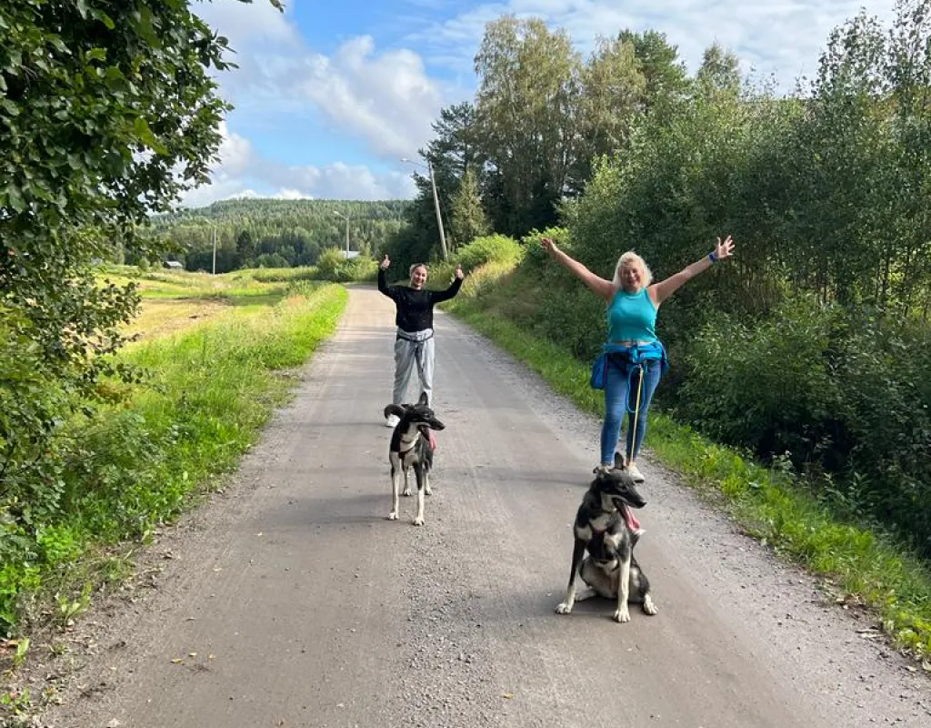 Två kvinnor och promenerar med husky
