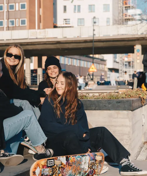 Tre tjejer som sitter vid skateparken spark