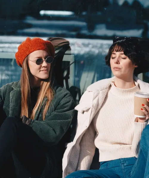 Två kvinnor dricker kaffe i vårsolen